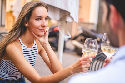 Beautiful woman holding drink sitting at restaurant