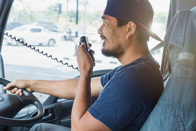 Midsection of man using mobile phone while sitting in car