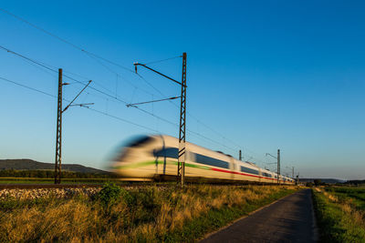 Train on railroad track against clear blue sky