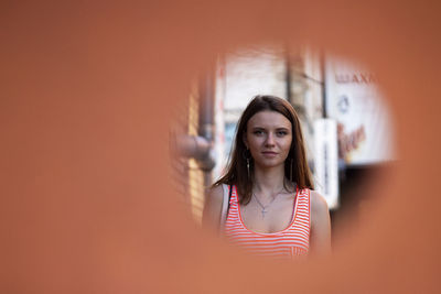 Portrait of young woman standing against wall