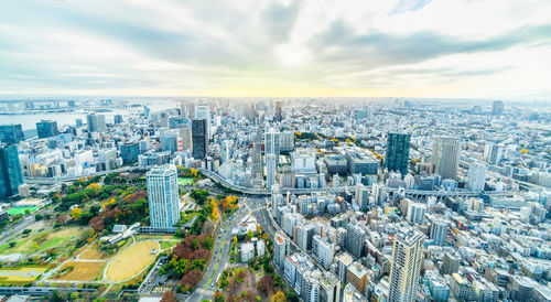 High angle view of city buildings against cloudy sky