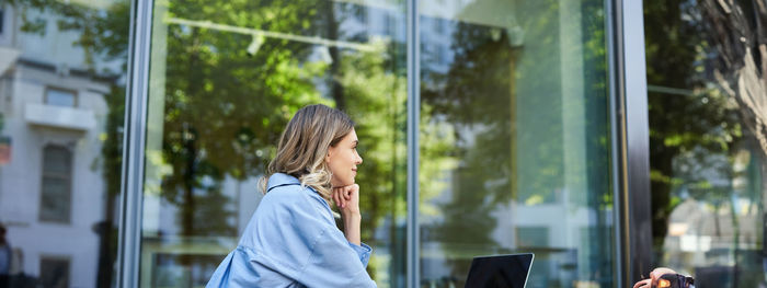 Side view of young woman looking through window