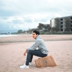 Side view of young man sitting on beach