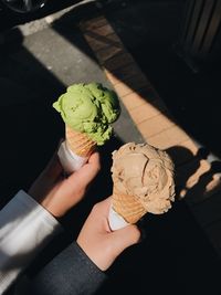 Cropped hands of friends holding ice cream cone outdoors