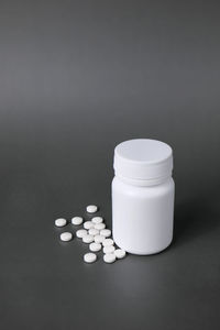 Close-up of pills spilling from bottle against white background