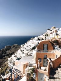 High angle view of townscape by sea against clear blue sky