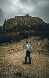 Hiker standing on land against mountain