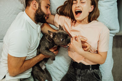 French bulldog bite woman's finger while they laying on the bed with man	
