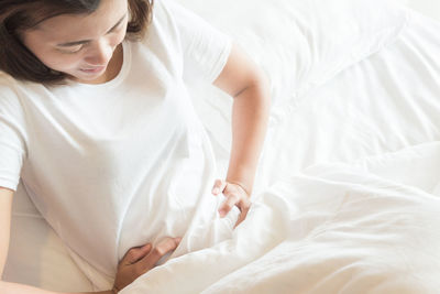 Midsection of young woman lying on bed