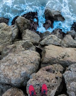 Low section of person on rock against sea