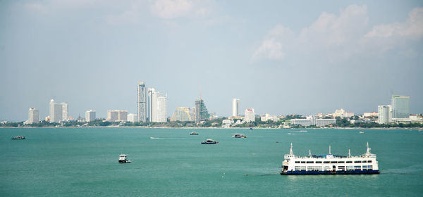 Nautical vessel on sea by buildings against sky