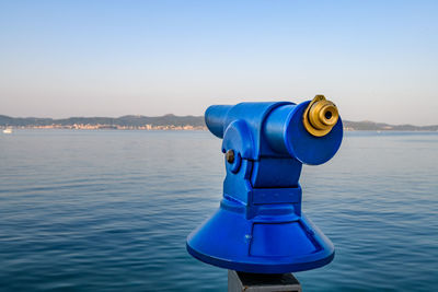 Close-up of coin-operated binoculars on sea against clear sky
