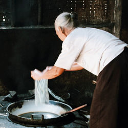 Side view of woman holding ice cream in kitchen