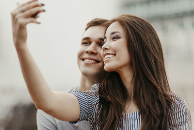 Smiling couple talking selfie in city during sunset