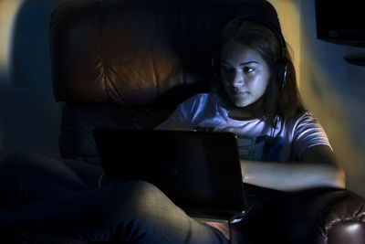 Cute girl using laptop sitting on sofa at home