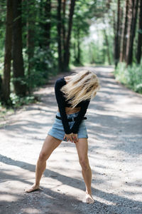 Rear view of woman walking on road in forest