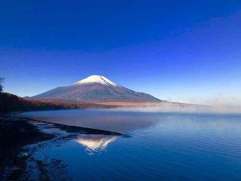 Scenic view of lake and mountains against clear blue sky