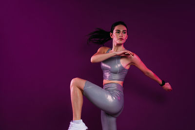 Portrait of young woman exercising against black background