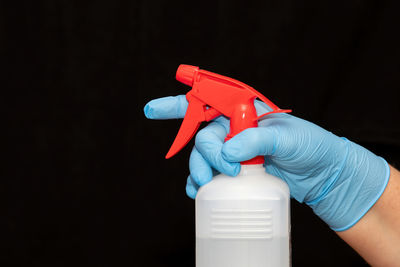 Close-up of hand holding bottle against black background