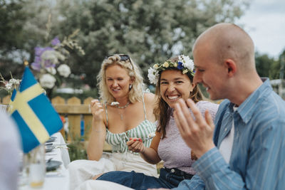 Happy young woman having cake while enjoying with friends during dinner party at cafe