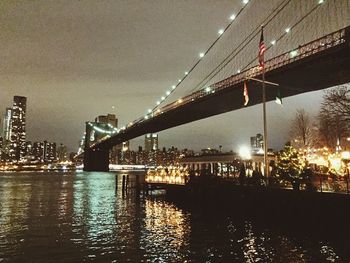 Illuminated bridge over river at night