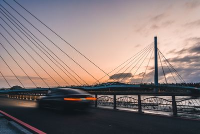 View of car on bridge against cloudy sky at sunset