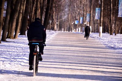 Rear view of woman riding bicycle on snow