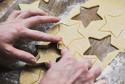 High angle view of woman hand cutting cookies on table
