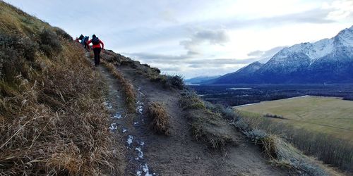 Rear view of people hiking on mountain against sky
