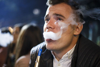 Close-up of man smoking hookah at night