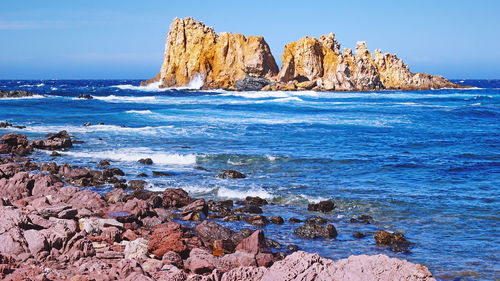 Scenic view of rocks in sea against sky