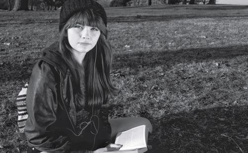 Portrait of young woman sitting on field