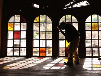 Rear view of man standing by window in building