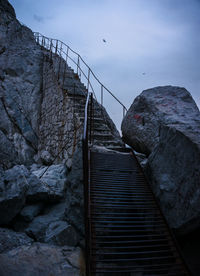 Low angle view of rocks by sea against sky