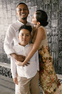 Portrait of siblings standing against wall