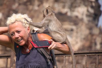 Monkey pulling hair of woman sitting on shoulder