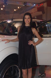 Portrait of smiling woman standing by car