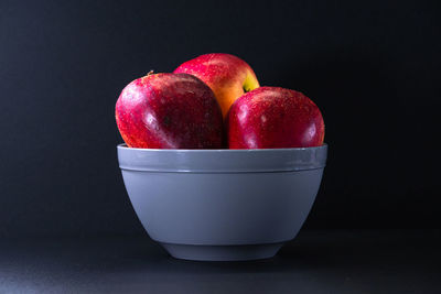 Close-up of apples in container against black background