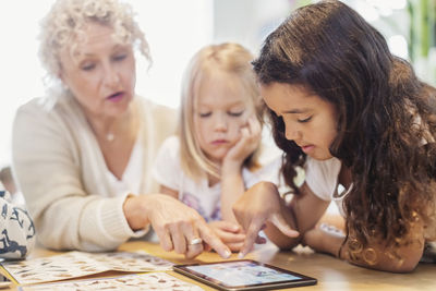 Senior female teacher and little girls using digital tablet