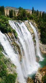 Scenic view of waterfall in forest against sky