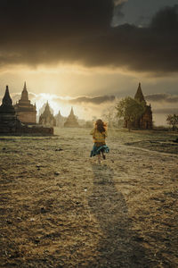 Woman sitting on temple by building against sky