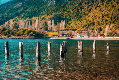 Wooden posts in lake against mountain