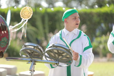 Man playing drum while standing outdoors in event