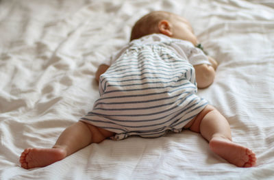 Midsection of baby sleeping on bed