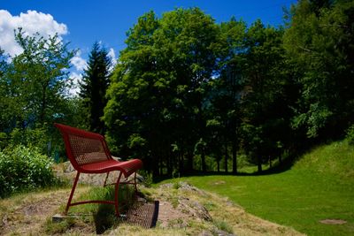 Empty chair in park against sky