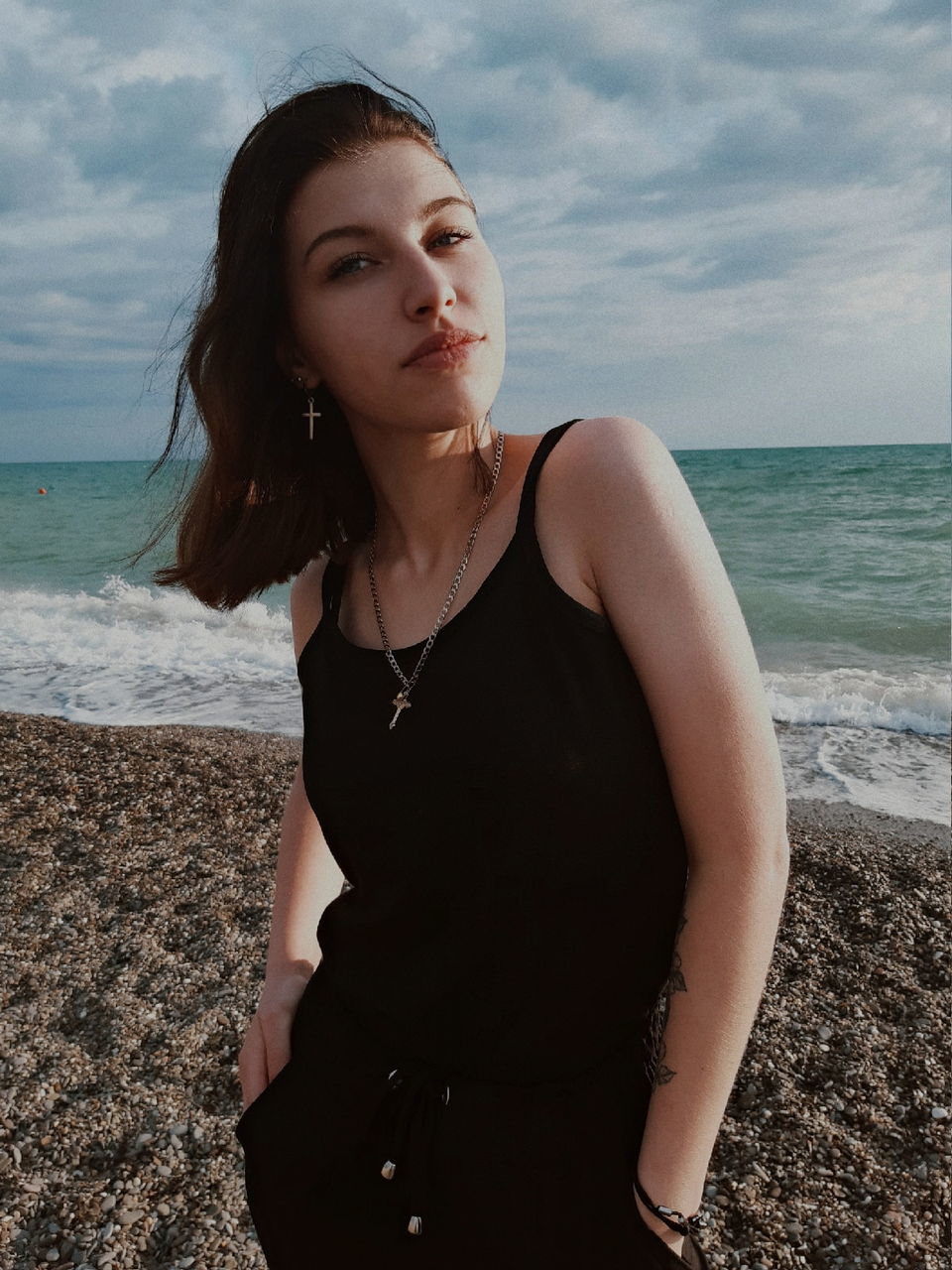 sea, one person, beach, female, water, land, sky, adult, women, young adult, nature, hairstyle, horizon over water, portrait, photo shoot, horizon, standing, long hair, dress, cloud, leisure activity, person, front view, clothing, blue, contemplation, three quarter length, looking, waist up, sand, beauty in nature, looking at camera, brown hair, serious, holiday, portrait photography, limb, lifestyles, day, vacation, outdoors, trip, casual clothing, teenager, human leg, fashion, tranquility, relaxation, ocean, black