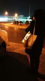 Low section of man on car moving on road at night