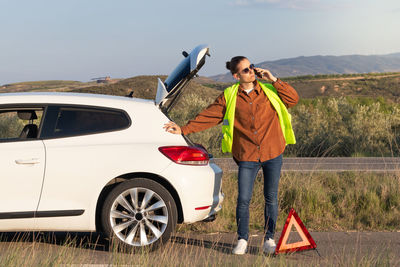 Young handsome modern man leaning on his white car after a breakdown in the middle of the road