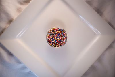 Directly above shot of multi colored candies in container on plate