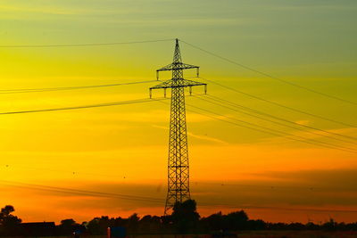 Low angle view of silhouette electricity pylon against romantic sky during sunset in the evening